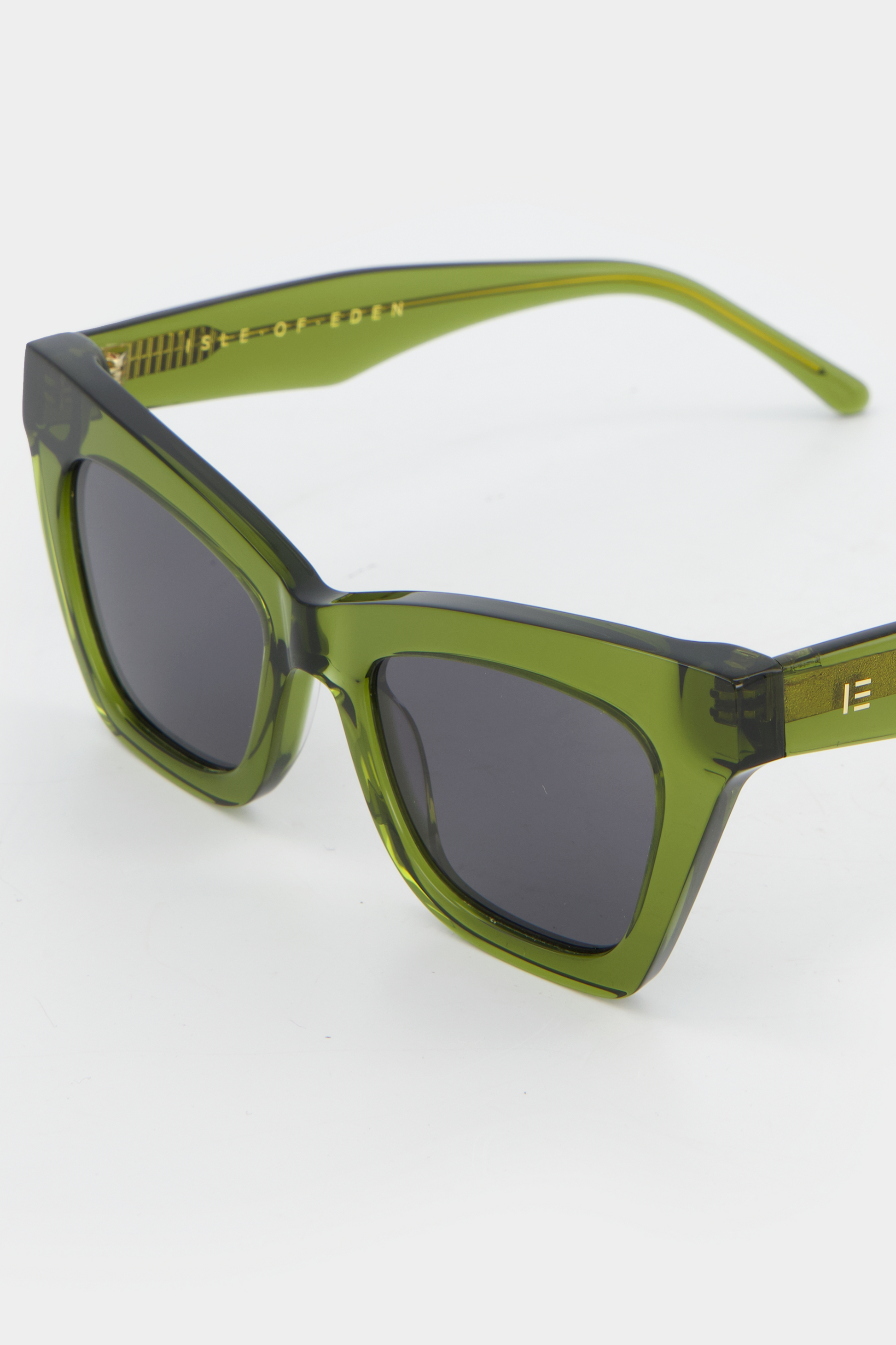 Close-up of Isle of Eden Sienna bottle green sunglasses showing angular cat-eye frame and brand lettering