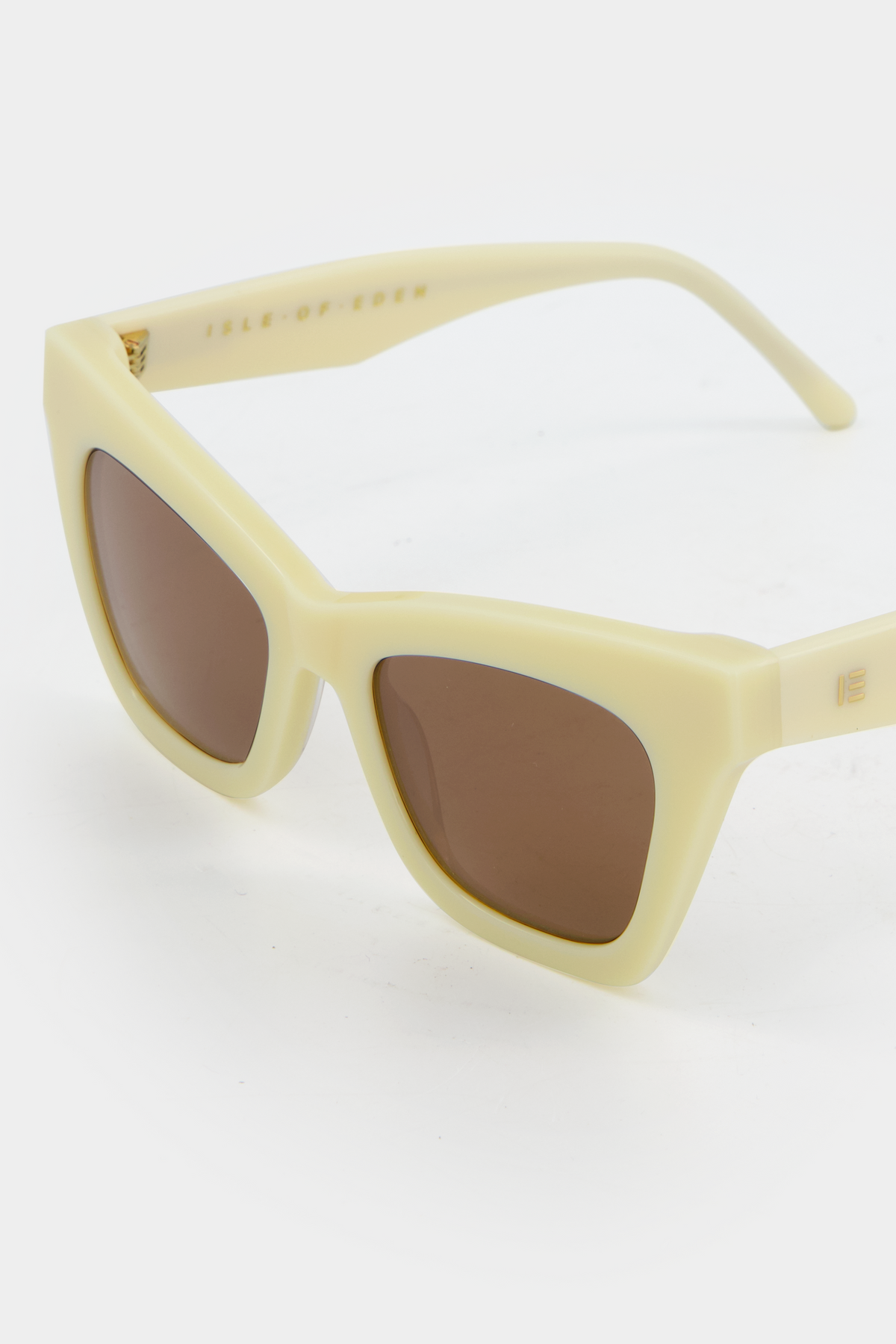 Close-up of Isle of Eden Sienna ivory sunglasses showing angular cat-eye frame and brand lettering