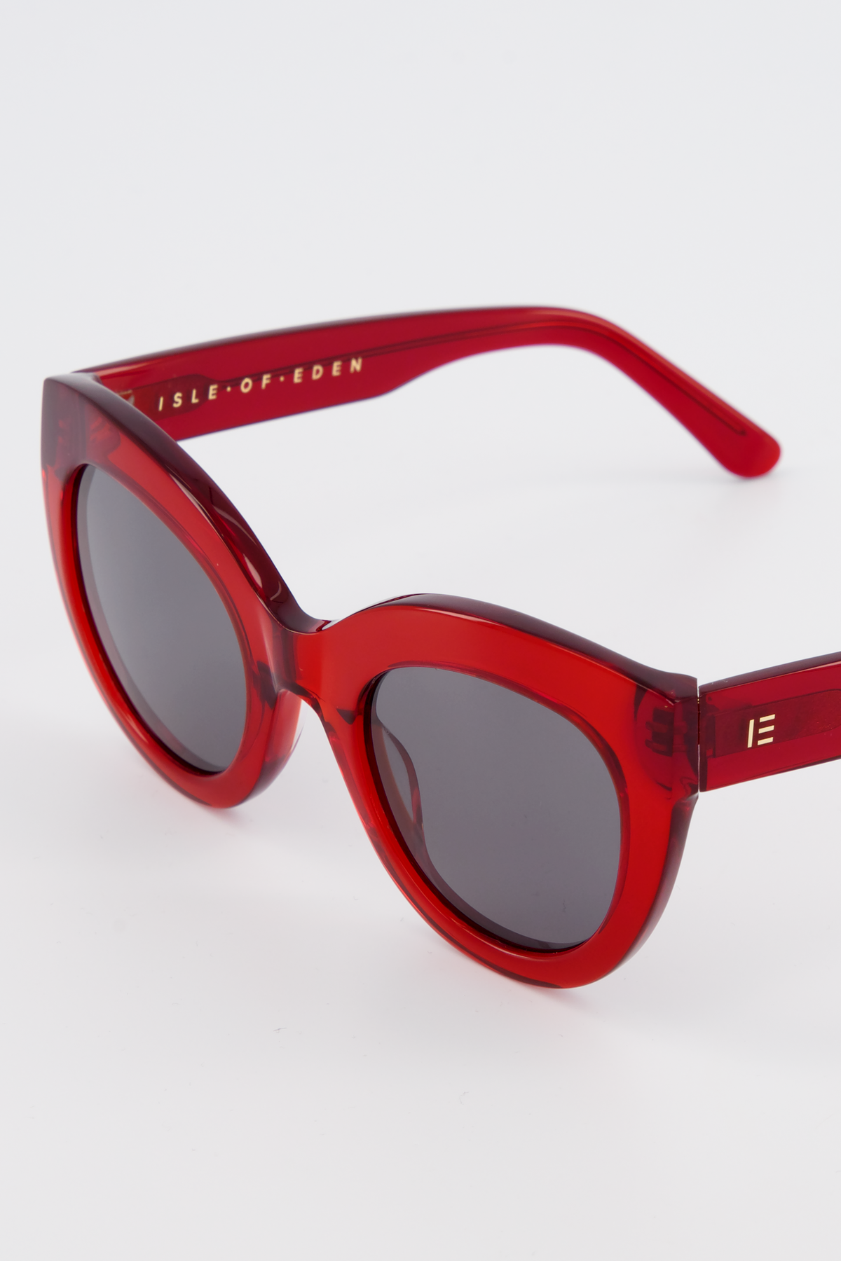 Close-up of Isle of Eden Wynnie red sunglasses showing oversized cat-eye frame and brand lettering
