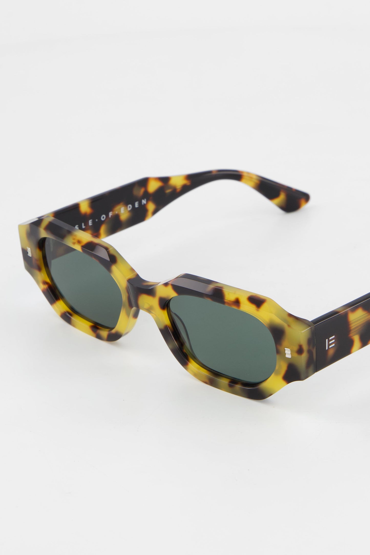 Close-up of Isle of Eden Blake tortoise sunglasses showing filigree wire temple core and brand lettering